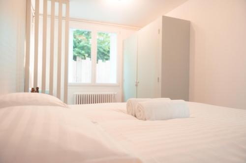 - une chambre blanche avec 2 serviettes blanches sur un lit dans l'établissement L'Unique- Maison de famille en Plein Centre-Ville, à Tours