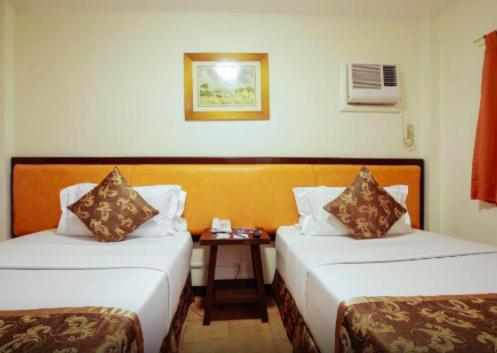 a hotel room with two beds and a table at Boracay Paradise Garden Hotel By Tripzy Fun in Boracay