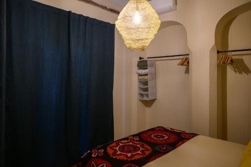 a bedroom with a blue curtain and a chandelier at Casa Del Encanto Arcos in Arcos de la Frontera