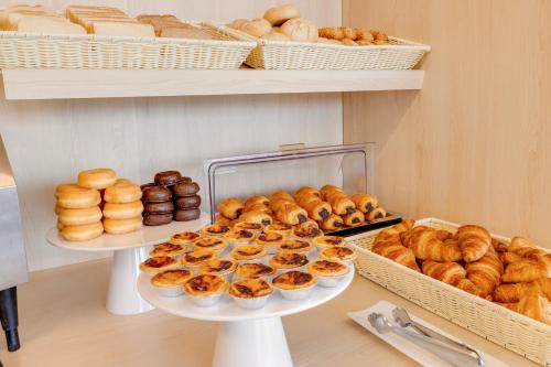 a bunch of donuts and other baked goods on shelves at B&B HOTEL Famalicão in Vila Nova de Famalicão