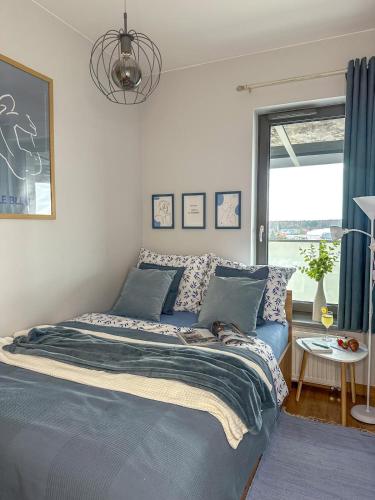 a bedroom with a bed with blue sheets and a window at Apartamenty Prestige Harmony Arnikowa in Augustów