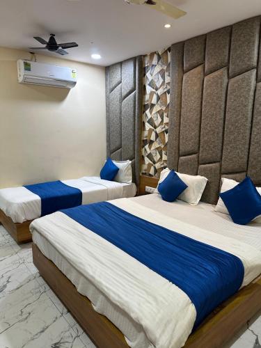 two beds in a hotel room with blue pillows at Hotel Royal King in Ahmedabad