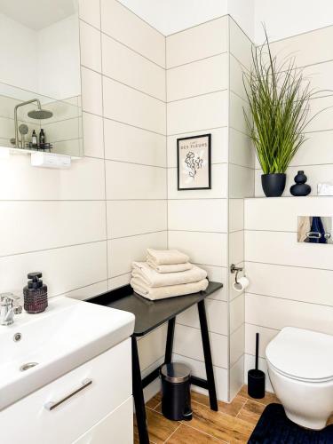 a white bathroom with a sink and a toilet at Apartamenty Prestige Harmony Arnikowa in Augustów