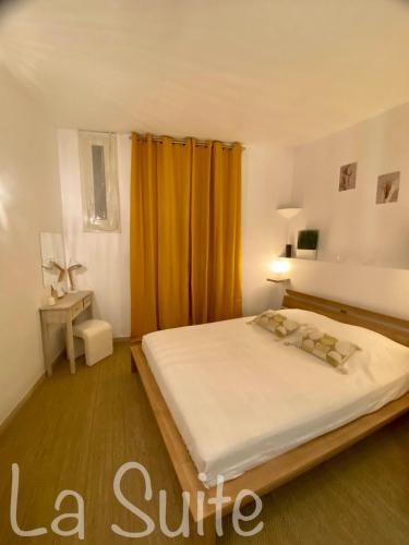 - une chambre avec un grand lit et un rideau jaune dans l'établissement La Suite, à Beausoleil