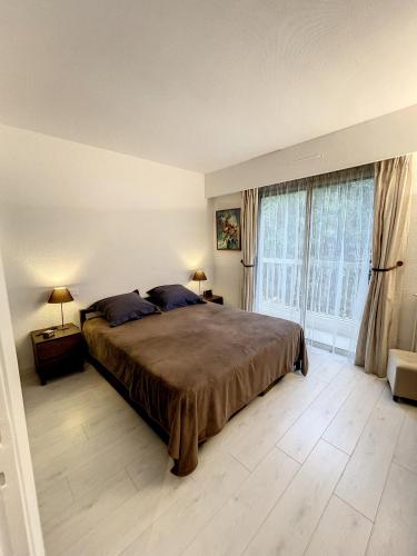une chambre avec un grand lit et deux fenêtres dans l'établissement Superbe appartement plage du Midi 2 piscines 325L, à Cannes