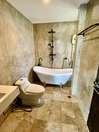 a bathroom with a tub and a toilet and a sink at Villa Coconut Khaolak in Khao Lak
