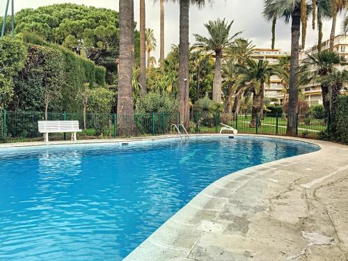 - une piscine avec un banc et des palmiers dans l'établissement A deux pas des plages piscine 346L FRANCHI, à Cannes