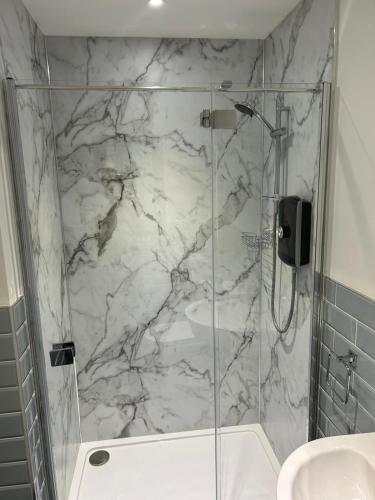 a bathroom with a marble shower with a glass door at Blundens Holiday Lets - Ffos Las in Chichester