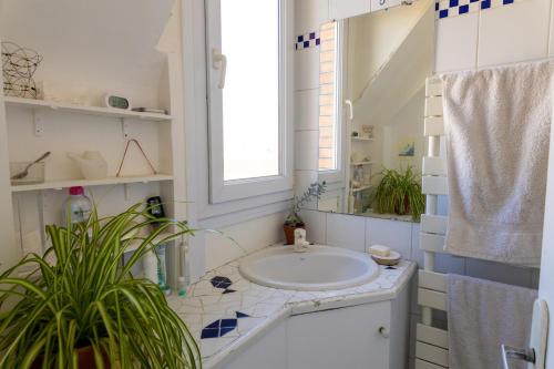 une salle de bain blanche avec un lavabo et une fenêtre dans l'établissement Two rooms with view near canal, à Paris