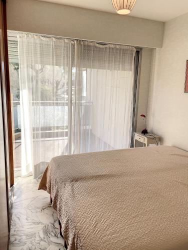 une chambre avec un lit et une grande fenêtre dans l'établissement A deux pas des plages du Midi 305L, à Cannes
