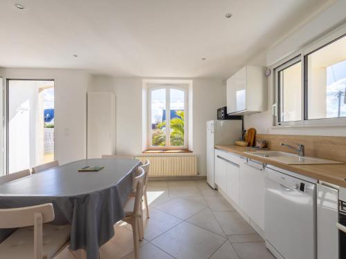 une cuisine avec une table et des placards blancs dans l'établissement Ti Ma Zud, à Pleumeur-Bodou