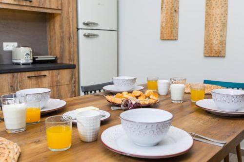 a wooden table with plates of food and glasses of orange juice at Ekaterini Luxury House in Lefkogeia
