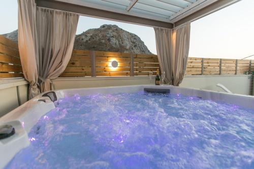 a jacuzzi tub in a room with a rock at Ekaterini Luxury House in Lefkogeia