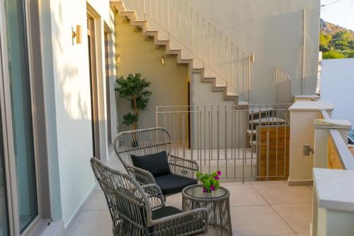 a balcony with chairs and a table and stairs at Ekaterini Luxury House in Lefkogeia