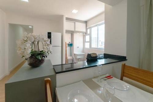 a kitchen with a counter with a vase of flowers on it at Apartamento Funcional no Coração da Cidade in Maringá
