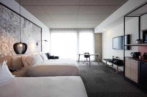 a hotel room with two beds and a desk at Hôtel Escad Quartier DIX30 in Brossard