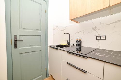 a white kitchen with a sink and a door at Homly Nook in Rīga