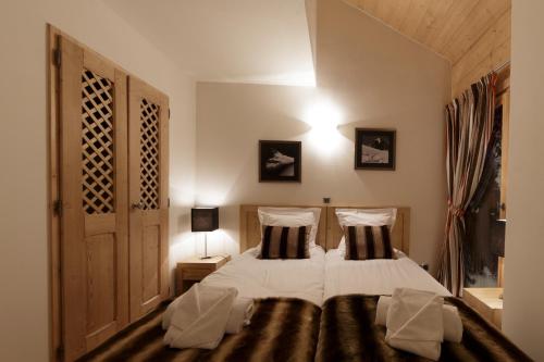 een slaapkamer met een bed met 2 kussens bij CGH Résidences & Spas Les Chalets De Laÿssia in Samoëns