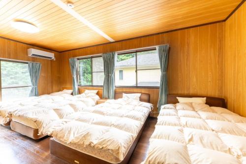 a row of beds in a room with wooden walls at Green Oasis Cottage B in Hakone