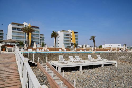 a group of lounge chairs and a pool with buildings at Condominio Náutico SOTAVENTO - PARACAS in Paracas