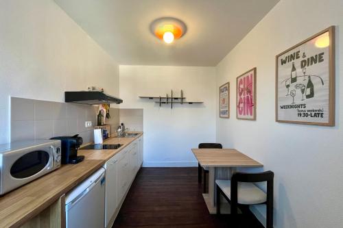 a small kitchen with a table and a microwave at Rutxhiel - Appartement 3e étage in Liège