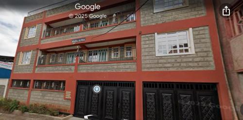 a brick building with black doors and a balcony at Angie's palace in Syokimau