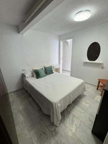een witte slaapkamer met een groot bed met blauwe kussens bij Iberia Apartment in Benidorm