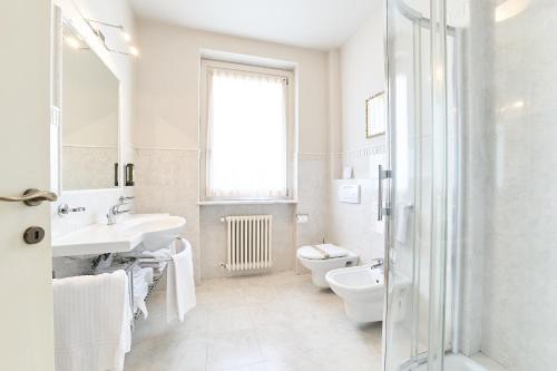 a white bathroom with a sink and a toilet at Hotel Belvedere Ranco in Ranco
