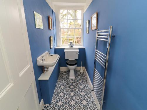 a blue bathroom with a sink and a toilet at Westward Park in Wigton
