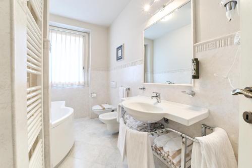 a white bathroom with a sink and a toilet at Hotel Belvedere Ranco in Ranco