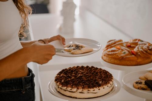 a woman is cutting a cake on a table with pastries at Biancodonda Greenblu Hotel & SPA in Gallipoli