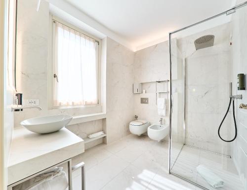 a white bathroom with a sink and a shower at Hotel Belvedere Ranco in Ranco