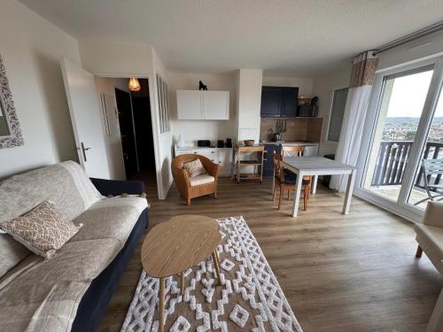 un salon avec un canapé et une table et une cuisine dans l'établissement Proche Mer - 2 pièces Balcon au SUD, à Cabourg