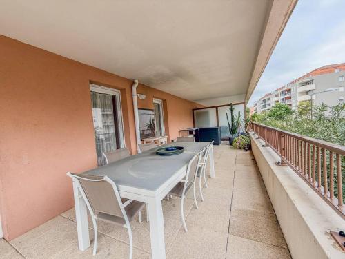 une table blanche et des chaises sur un balcon dans l'établissement T3 dans Résidence avec Piscine , plage à pieds et proche commerces, au Lavandou