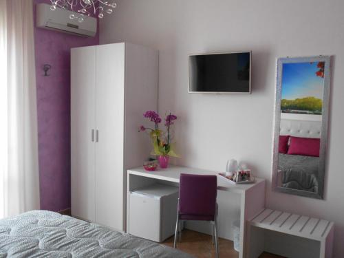 1 dormitorio con escritorio y silla morada en Capital Bed Porto Cesareo, en Porto Cesareo