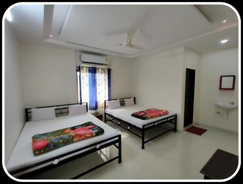 a room with two beds and a sink in it at Gurucharan in Shirdi
