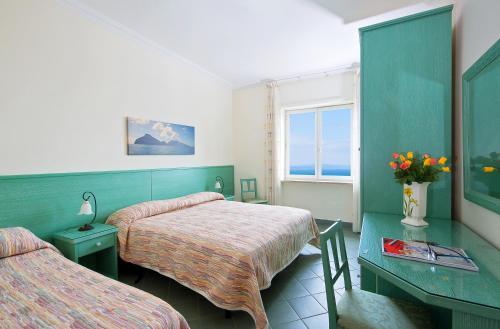 um quarto com duas camas e uma mesa com flores em Da Giorgio em Capri