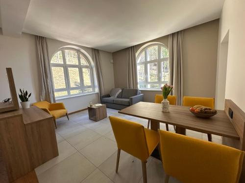 a living room with a wooden table and yellow chairs at Domaine de Haslach, The Originals Collection, Résidence de Tourisme in Munster