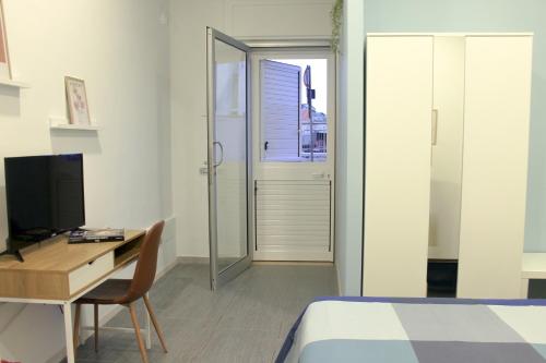 a bedroom with a bed and a desk and a television at di fronte al museo in Gela