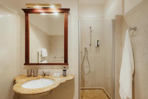 ein Badezimmer mit Waschbecken und Dusche mit Spiegel in der Unterkunft Corso am Graben in Bruneck