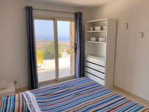 Un dormitorio con una cama y una puerta corrediza de vidrio. en Villa Carina, en Tertenìa