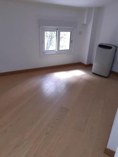 Cette chambre vide est dotée de parquet et d'une fenêtre. dans l'établissement Chambre a louer a Nogaro, à Nogaro