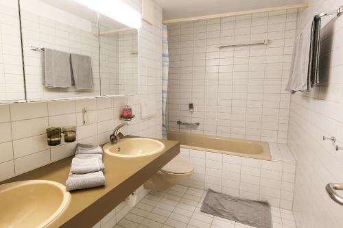 a bathroom with a sink and a toilet and a tub at Hotel Grüsch in Grüsch