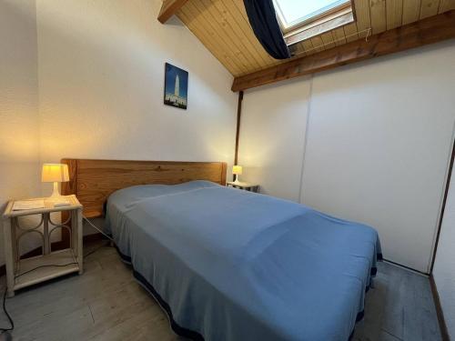 ein Schlafzimmer mit einem blauen Bett und einem Fenster in der Unterkunft Mais 4 pièces Oléron 6 couchages - SAINT-DENIS D'OLERON SDO000-013 in Saint-Denis-dʼOléron