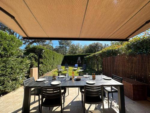 une table et des chaises sur une terrasse sous un parasol dans l'établissement Mini Villa à 3 minutes de la plage de Pinarello, à Pinarellu