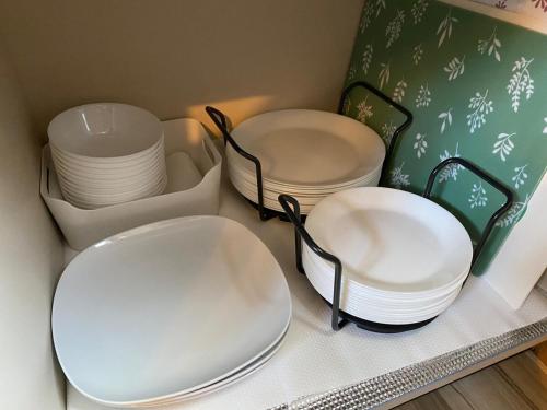 three white plates and bowls sitting on a shelf at 富士山を背景に豊かな自然やバーベキューが魅力のコテージ Sakura in Kannami