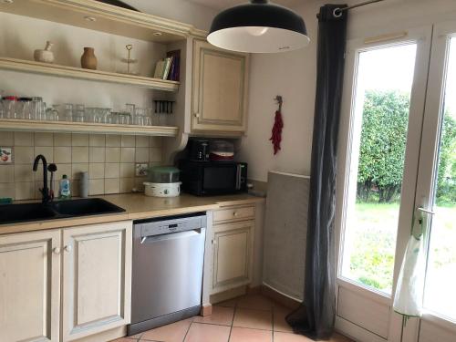 a kitchen with white cabinets and a sink and a window at Maison les rives Ardéchoises in Ucel