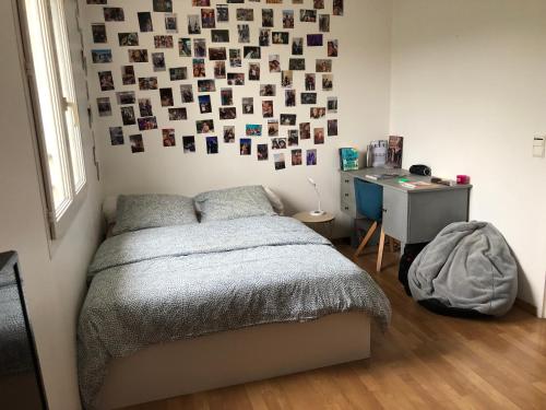 a bedroom with a bed and a desk and a wall with pictures at Maison les rives Ardéchoises in Ucel