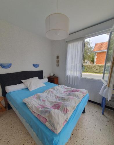 une chambre avec un lit avec une grande fenêtre dans l'établissement villa au coeur de soulac, à Soulac-sur-Mer