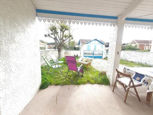 une terrasse couverte avec des chaises, une table et une maison dans l'établissement villa au coeur de soulac, à Soulac-sur-Mer